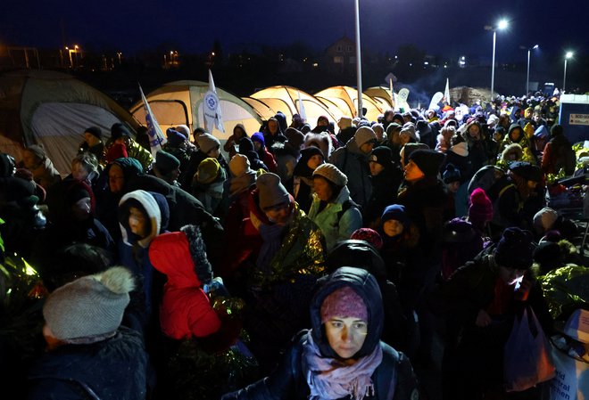 Begunci čakajo prevoz po prečkanju mejnega prehoda med Ukrajino in Poljsko Medyka. FOTO: Fabrizio Bensch/Reuters
