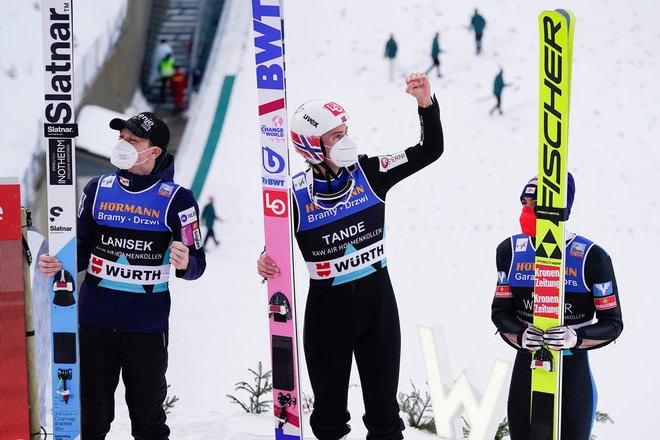 Norveški zvezdnik Daniel-Andre Tande (v sredini) je slabo leto po grozljivem padcu v Planici slavil zmago na Holmenkollnu. Na odru za najboljše smučarske skakalce na svetu sta mu v nedeljo družbo delala slovenski as Anže Lanišek (levo) in Avstrijec Stefan Kraft. FOTO: Terje Bendiksby/Reuters
