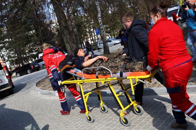 Po raketnem napadu na vojaško bazo Javoriv blizu poljske meje reševalci oskrbujejo ranjence. FOTO:&nbsp;Kai Pfaffenbach/Reuters
