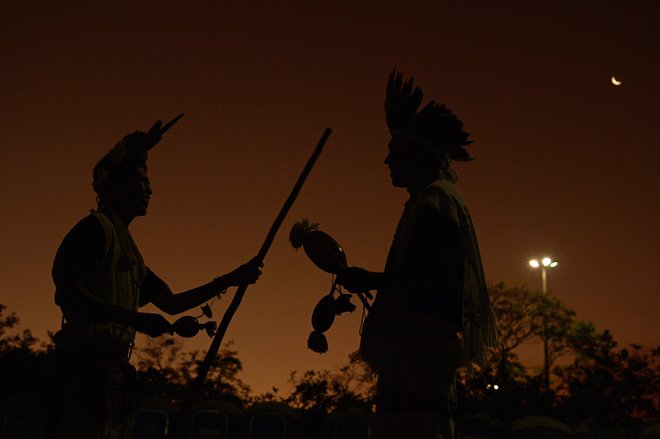 Člani brazilskih avtohtonih plemen se med sončnim zahodom pogovarjajo na prvi dan tabora avtohtonih prebivalcev Terra Livre v Brasilii. Na desetdnevnem protestu, ki ga zadnja leta organizirajo člani domorodnih plemen iz vse Brazilije, pozivajo k večji zaščiti svoje zemlje in pravic. Foto: Carl De Souza/Afp
