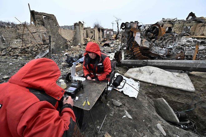 Ukrajinci popravljajo in obnavljajo lokalne komunikacijske kable med ruševinami v mestu Buča, na obrobju ukrajinske prestolnice Kijev. Foto: Genya Savilov/Afp
