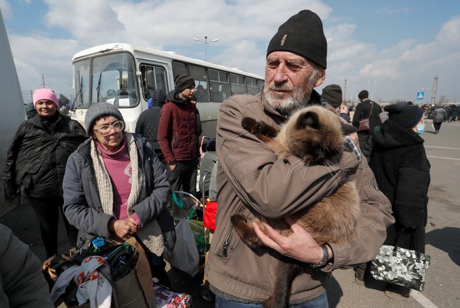 Moški z mačko in drugi begunci pred evakuacijo iz obleganega Mariupolja 5. aprila. FOTO: Alexander Ermochenko/Reuters
