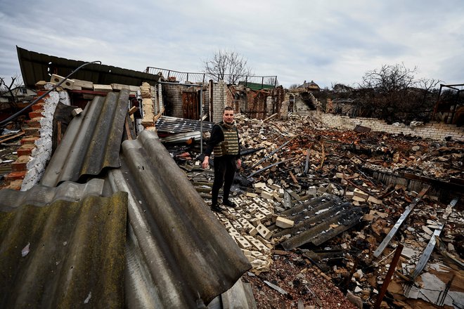 32-letni humanitarni delavec Oleksandr Markov med ruševinami hiše svojih staršev v Černigovu. FOTO: Zohra Bensemra/Reuters
