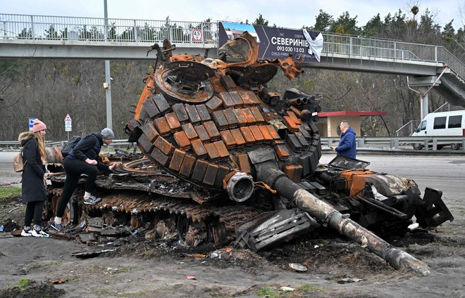 Prebivalci vasi Buzova zahodno od Kijeva ob uničenem ruskem tanku. FOTO: Sergei Supinsky/AFP
