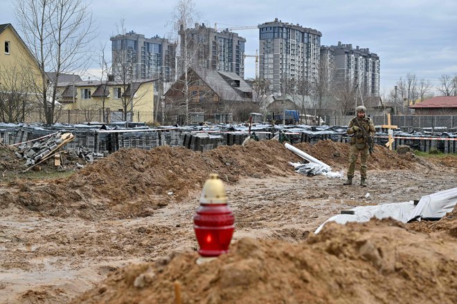 Ukrajinski stražar ob množičnem grobišču v Buči. FOTO: Sergei Supinsky/AFP
