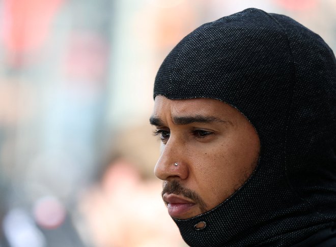 Med dirkanjem ima Lewis Hamilton pokrita ušesa. FOTO: Loren Elliott/Reuters
