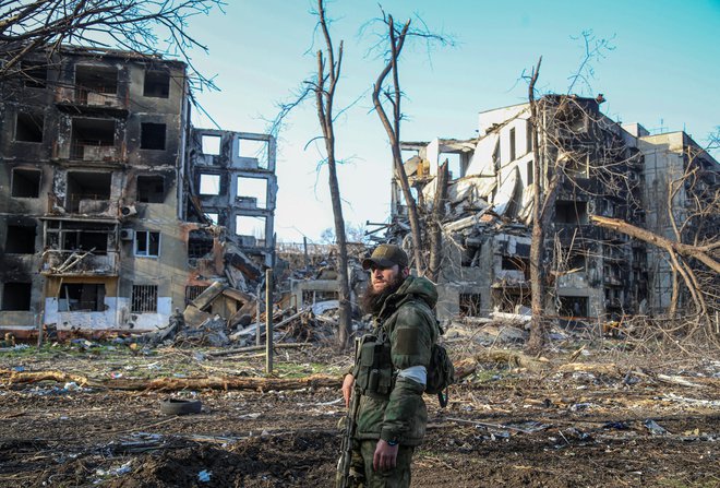 Čečenski vojak pozira fotografu pred uničenimi stanovanjskimi stavbami v Mariupolju. FOTO:&nbsp;Reuters
