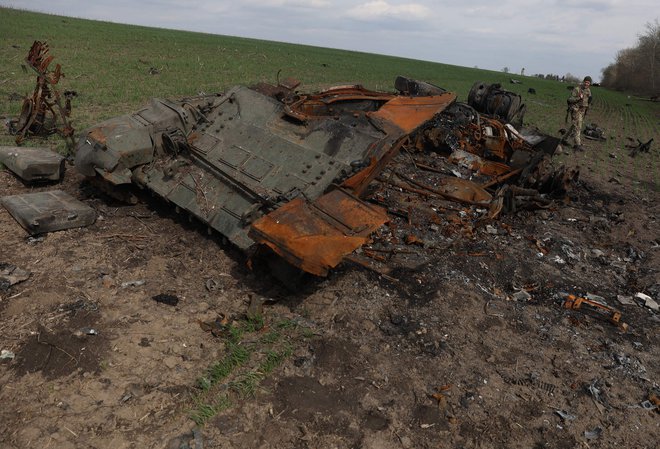 Ukrajinski vojaški pripadnik hodi mimo uničenega ruskega tanka v bližini vasi Gusarovka v Harkovski regiji. FOTO: Anatolii Stepanov/AFP
