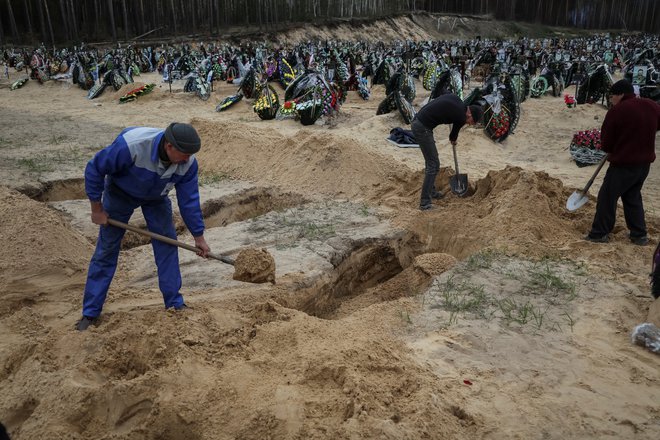 Kopanje grobov ubitih v obstreljevanju v okolici Kijeva. FOTO: Gleb Garanich/Reuters
