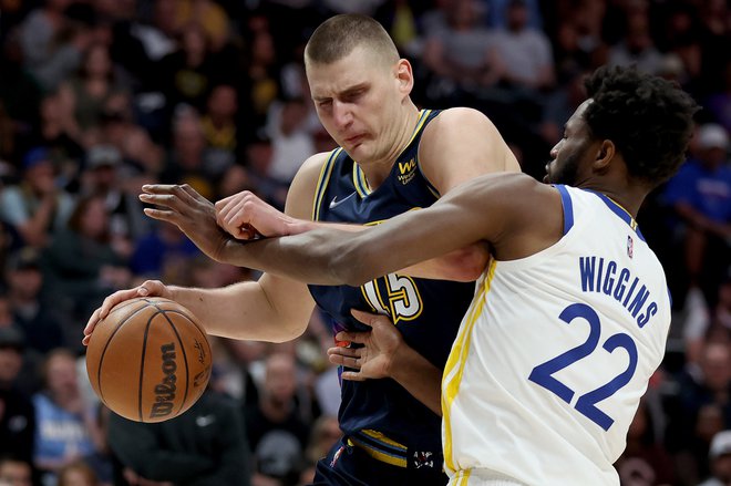 Nikola Jokić&nbsp;prodira ob Andrewu Wigginsu&nbsp;na četrti tekmi serije v dvorain Ball Arena v Denverju. FOTO: Matthew Stockman/AFP
