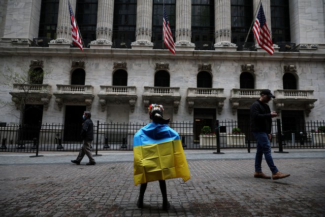 Neustrašno deklico pred poslopjem borze v New Yorku so ogrnili v ukrajinsko zastavo. FOTO: Shannon Stapleton/Reuters
