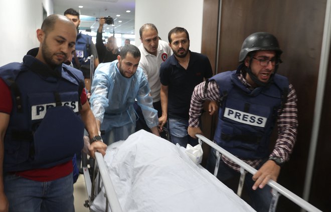 Novinarji v bolnišnici v Džaninu spremljajo truplo novinarske veteranke Al Džazire Shireen Abu Aqleh, ki so jo ustrelili izraelski vojaki, ko je poročala o raciji v begunskem taborišču Jenin na Zahodnem bregu. Okoliščine njene smrti še niso jasne, a video posnetek dogajanja prikazuje da je bila Abu Akleh ustreljena&nbsp; v glavo. Foto: Jaafar Ashtiyeh/Afp
