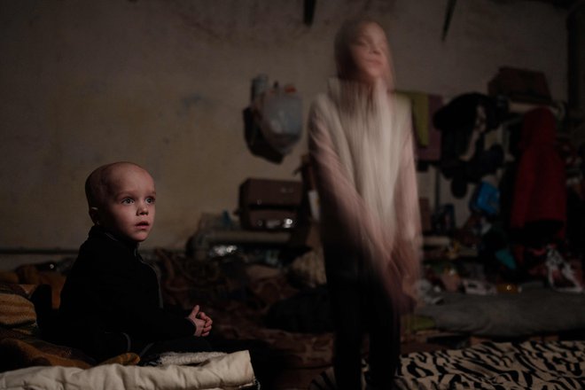 Štiriletni Saša in njegova osemletna sestra Ksenija, otroka ukrainske družine, ki se ni odločila za evakuacijo, pozirata v spalnici kletnega zaklonišča v mestu Lysychansk na vzhodu države. Foto: Yasuyoshi Chiba/Afp
