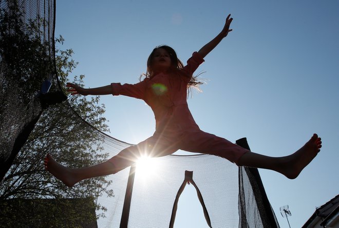 Milly aged 7 jumps on a trampoline in her garden while she takes a break from home schooling as the spread of the coronavirus disease (COVID-19) continues, in Hertford, Britain, March 27, 2020. REUTERS/Andrew Couldridge