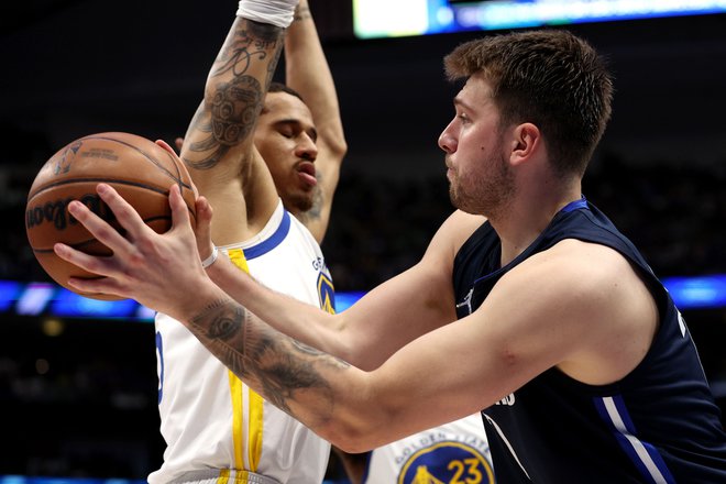 Luka Dončić v prodoru ob Juanu Toscano-Andersonu na tretji tekmi konferenčnega finala v Dallasu. FOTO: Tom Pennington/AFP
