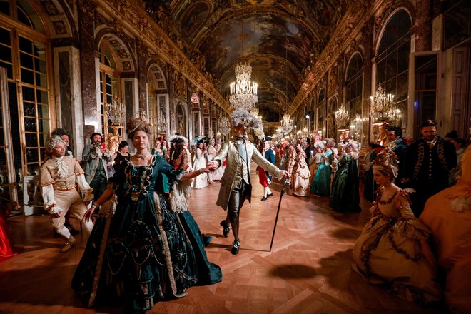 Gostje v kostumih baročnega sloga se sprehajajo po dvorani ogledal v palači Chateau de Versailles v okviru šeste izdaje gala večera Fetes Galantes, katerega tema je kraljeva poroka Marie Antoinette in Ludvika XVI. Namen vsakoletnega plesa v kostumih je poustvariti baročni blišč bleščečih dvornih pojedin kralja sonca, ki so bile organizirane za razkazovanje bogastva in moči najdlje vladajočega francoskega monarha. Z vstopnico, ki stane več kot petsto evrov, se lahko gostje sprehodijo po zasebnih apartmajih gradu, ki je uvrščen na seznam svetovne dediščine in ena največjih francoskih turističnih znamenitosti. Foto: Ludovic Marin/Afp
