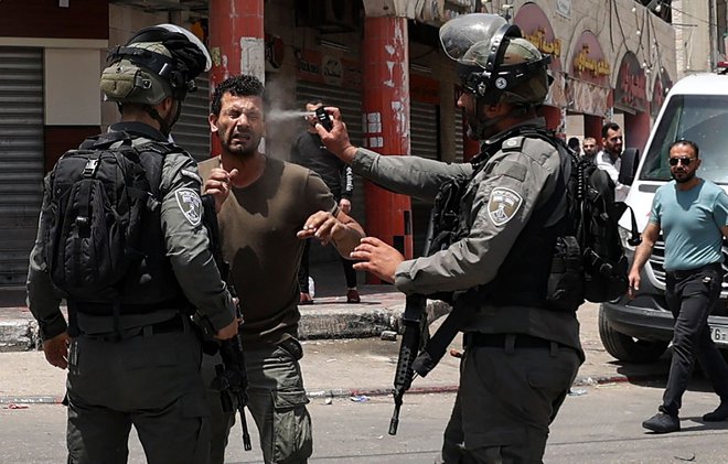 V mestu Hauwara na Zahodnem bregu&nbsp;med spopadi je izraelski mejni policist palestinskemu protestniku v obraz brizgnil solzivec. Foto: Jaafar Ashtiyeh/Afp
