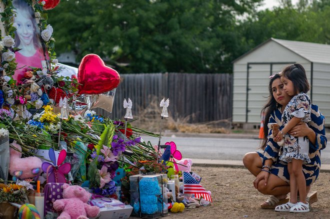 Ženska in otrok sta se poklonila spomeniku, posvečenemu 19 otrokom in dvema odraslima, ki so bili ubiti 24. maja med množičnim streljanjem v osnovni šoli Robb. FOTO: Brandon Bell/AFP
