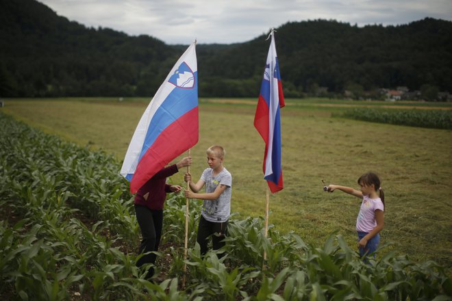 Družina s slovenskima zastavama pričakuje prihod kolesarjev. FOTO: Jure Eržen/Delo
