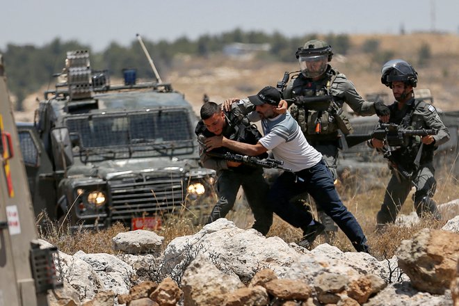 Palestinec se spopada z izraelskimi silami med protestom proti izraelskemu naseljevanju v bližini Hebrona na Zahodnem bregu, ki ga zaseda Izrael. Foto: Mussa Issa Qawasma/Reuters
