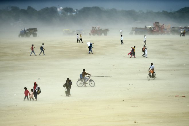 Na vroč poletni dan se ljudje sprehajajo med peščenim viharjem na Sangamu, sotočju rek Ganges, Yamuna in mitske Saraswati v Allahabadu. Foto: Sanjay Kanojia/Afp
