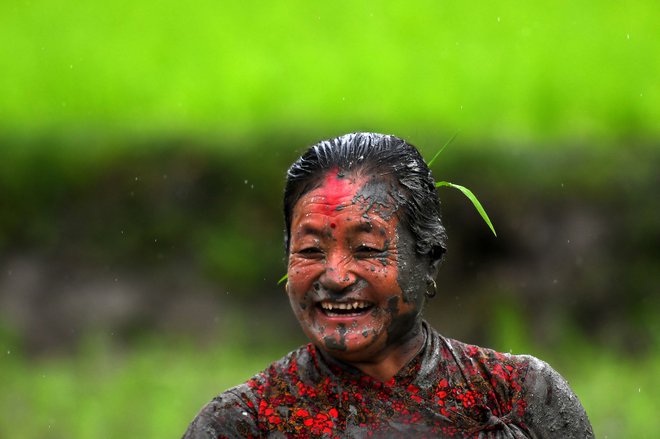 Blatna kmetica se smehlja na riževem polju med nacionalnim dnevom riža, ki zaznamuje začetek letne sezone sajenja riža, v vasi Tokha na obrobju Katmanduja. Foto: Prakash Mathema/Afp
