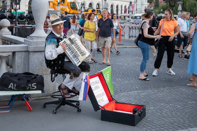 Harmonikar na Tromostovju je postal maskota prestolnice, a njegova navzočnost marsikoga moti. FOTO: Voranc Vogel/Delo
