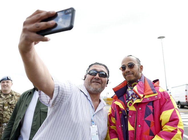 Lewis Hamilton je ob prihodu v Silverstone ustregel prošnjo enemu od navijačev in se fotografiral z njim. FOTO: Peter Cziborra/Reuters
