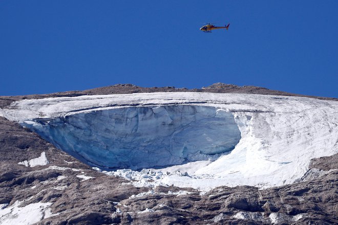 Reševalni helikopter med iskanjem pogrešanih v sobotni nesreči na ledeniku na gori Marmolada.&nbsp;FOTO:&nbsp;Guglielmo Mangiapane/ Reuters
