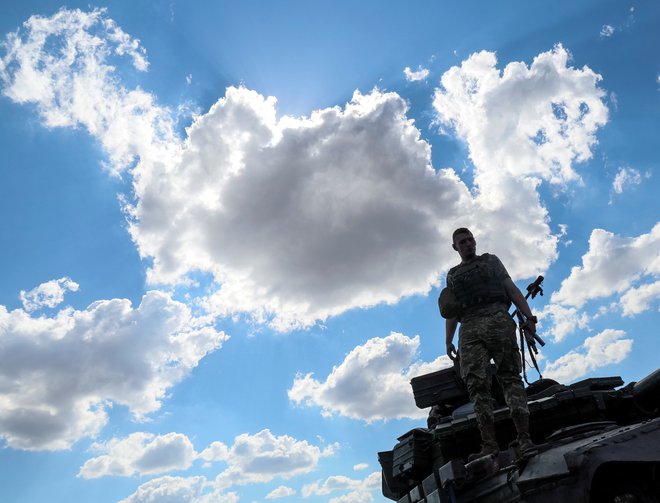 Ukrajinski vojak stoji na tanku, ki je naložen na vojaškem vozilu. FOTO: Gleb Garanich/Reuters
