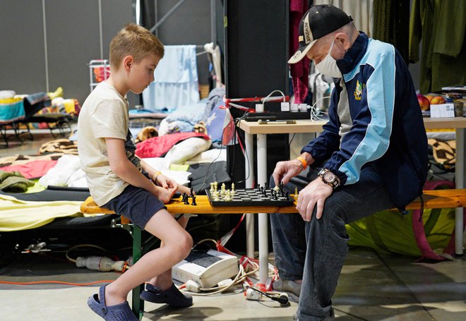 Begunci iz Ukrajine igrajo šah v centru za humanitarno pomoč, ki je bil postavljen na razstavnem prostoru Global Expo v Varšavi. Začasni center za begunce naj bi bil začasna rešitev. Foto: Alik Keplicz/Afp
