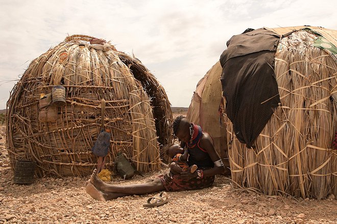 Ženska doji svojega otroka pred začasno hišo na območju Loiyangalani, kjer živijo družine, ki jih je prizadela dolgotrajna suša v Marsabitu. Najmanj 18 milijonov ljudi v Keniji in okoliških državah se sooča s hudo lakoto, saj regijo pustoši najhujša suša v zadnjih 40 letih. Več kot štiri milijone jih je na pogosto pozabljenem kenijskem severu, število pa se letos vztrajno povečuje tudi zaradi finančne krize. Foto: Simon Maina/Afp
