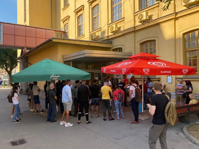 Pred vhodom v stavbo na Tobačni je vsak dan vrsta čakajočih. Vanjo spuščajo največje število ljudi, ki jih čakalnica prenese, saj trenutno poteka prenova prostorov. FOTO: Bralec Dela
