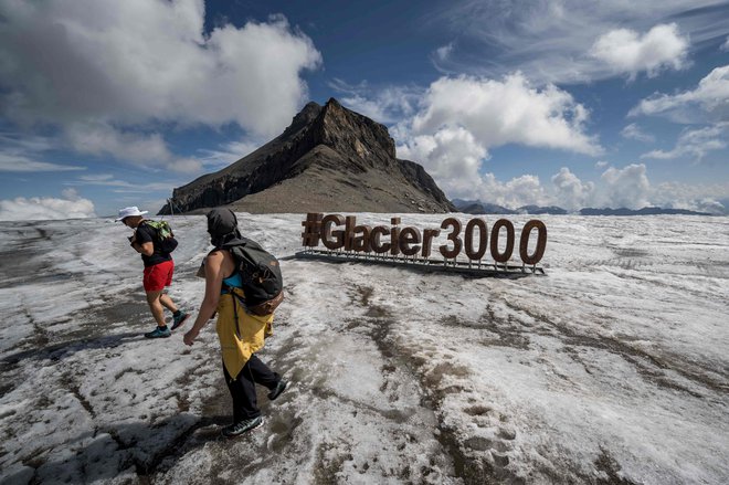 Turisti se sprehajajo na ledeniku Tsanfleuron nad Les Diableretsom v Švici. Po več vročinskih valovih, za katere znanstveniki krivijo podnebne spremembe, se v Švici vse hitreje talijo alpski ledeniki. Foto: Fabrice Coffrini/Afp
