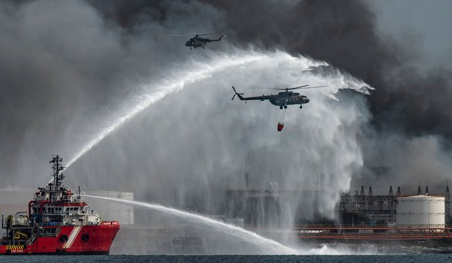 Mehiško gasilsko plovilo in helikopterji se v Matanzasu na Kubi trudijo zajeziti večdnevni požar v skladišču goriva, ki ga je povzročila strela. Obsežen požar, ki je vzplamtel v petek, je uničil štiri rezervoarje in ogroža še štiri, v njem pa je po navedbah oblasti umrl 60-letni gasilec, 14 kolegov pa pogrešajo. Več kot 100 ljudi je bilo poškodovanih, 22 jih je še vedno hospitaliziranih. Foto: Yamil Lage/Afp
