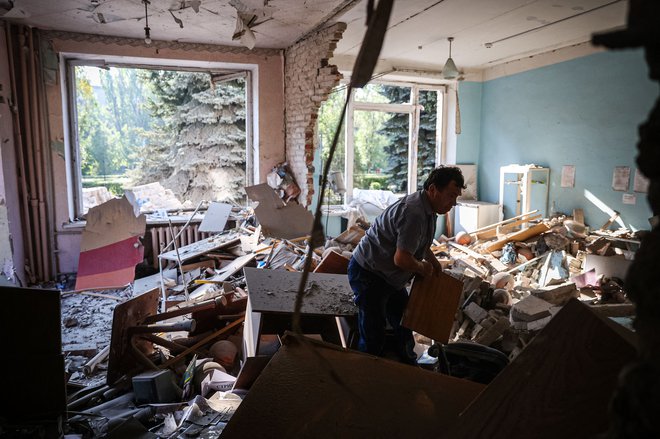 A man searches for surviving items in a school destroyed by a missile strike in the town of Kramatorsk, in Donetsk region, on August 19, 2022, amid the Russian military invasion of Ukraine. (Photo by ANATOLII STEPANOV / AFP)