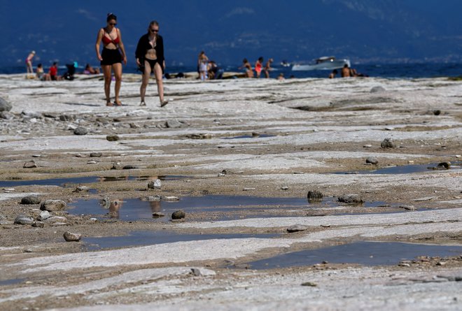 Gardsko jezero je dobilo povsem drugačno podobo. Razkrile so se velike bele skale, ki pa so ponekod zelo spolzke in zato nevarne za obiskovalce. FOTO: Flavio Lo Scalzo/Reuters
