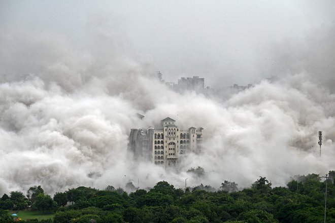 Stanovanjska soseska na obrobju New Delhija je zajeta v prah, potem ko so mestne oblasti z nadzorovano eksplozijo porušile 100 metrov visoka nezakonito zgrajena stanovanjska stolpa &raquo;Twin Towers&laquo;. To je bil redek ukrep zoper gradbenike, ki se izmikajo in goljufajo nič hudega sluteče kupce stanovanj. Foto: Sajjad Hussain Afp
