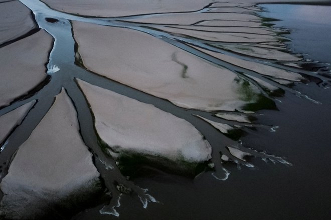 Pogled na pritok, ki teče skozi izsušene ravnice kitajskega jezera Poyang, kjer je zaradi suše rekordno nizka raven vode. Foto: Thomas Peter/Reuters
