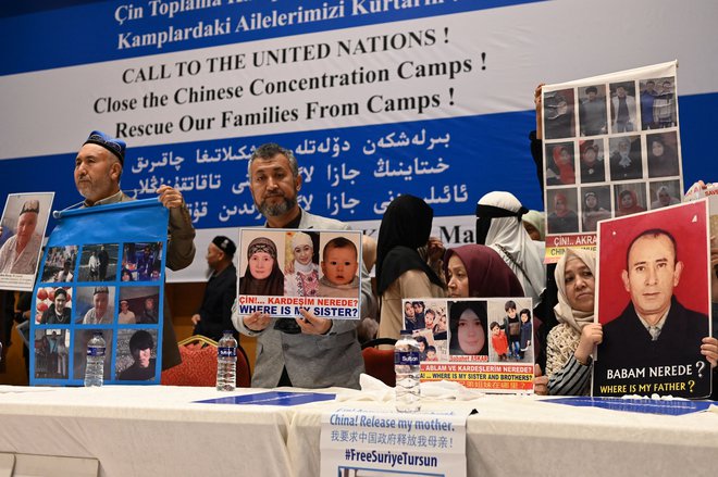 Pripadniki muslimanske ujgurske skupnosti kažejo fotografije svojih sorodnikov, ki so pridržani na Kitajskem. FOTO: Ozan Kose/AFP
