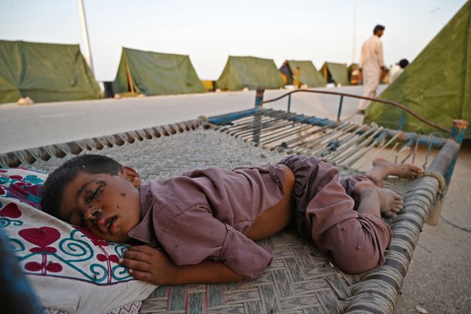 Na obrazu dečka, ki spi pred šotorom v začasnem taborišču v pakistanski provinci Sindh, je polno muh. Skoraj tretjina Pakistana je pod vodo (območje v velikosti Združenega kraljestva) po mesecih rekordnega monsunskega deževja, v katerem je umrlo 1300 ljudi ter odplaknilo več kot milijon domov. Foto: Aamir Qureshi/Afp
