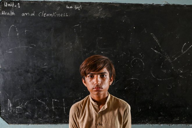 Pakistanski deček Nur Mohammad, ki so ga po močnem monsunskem deževju prizadele poplave, se je zatekel v šolo v pakistanskem mestu Jacobabad. Foto: SindhAamir Qureshi/Afp
