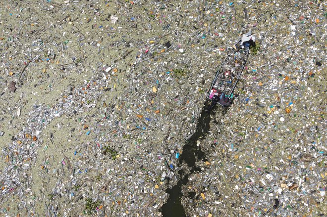 Na salvadorskem rezervoarju Cerron Grande v mestu Potonico moški zbirajo odpadno plastiko, steklo in druge materiale. Ogromne raznobarvne plastične usedline, ki priplavajo iz različnih pritokov, kot odeja prekrivajo mirne vode jezera Suchitlan. Enako se dogaja na rajskih plažah honduraškihh Karibov, na katere iz Gvatemale prihaja na tisoče ton odpadkov. Foto: Camilo Freedman/Afp
