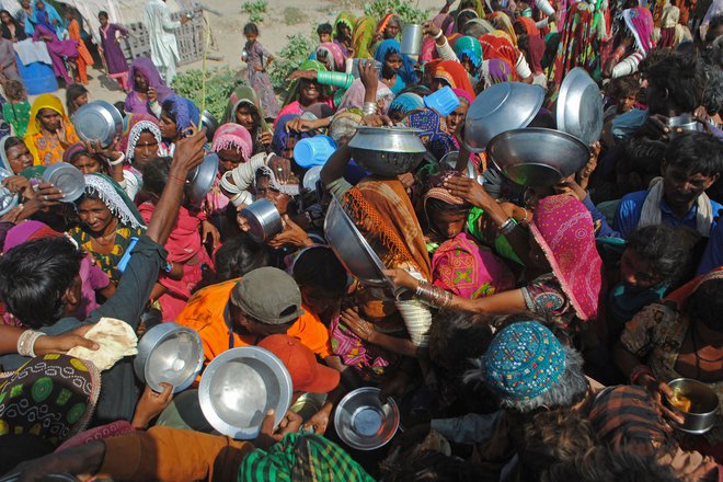 Notranje razseljeni Pakistanci se zbirajo, da bi prejeli brezplačno hrano v bližini svojega začasnega taborišča v provinci Sindh, ki so jo prizadele poplave epskih razsežnosti. Foto: Afp
