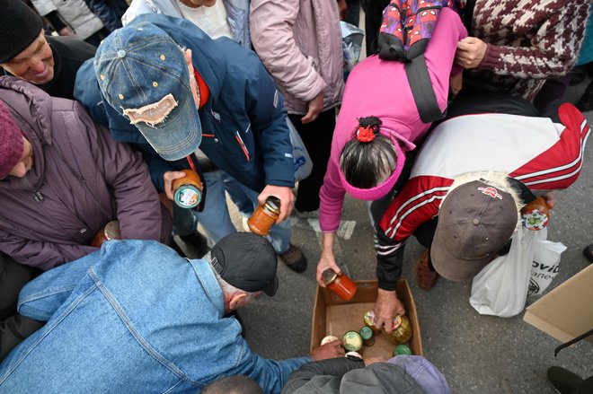 Humanitarna pomoč v obliki hrane, ki jo je priskrbela krščanska verska organizacija, se razdeljuje lokalnim prebivalcem v ukrajinskem mestu Izjum. FOTO: Sergej Bobok/AFP
