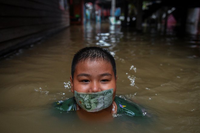Tajski deček se igra na poplavljeni cesti po obilnem deževju v bližini mošeje Tha-it na obrobju Bangkoka. Foto: Chalinee Thirasupa/Reuters
