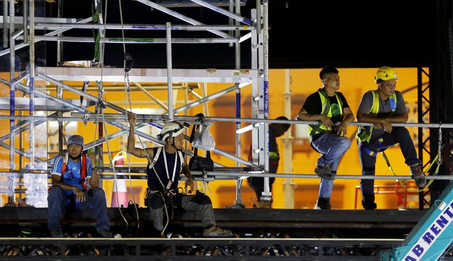 Delavci v eni najbogatejših držav na svetu prejemajo le dober evro plačila na uro, delajo pa krepko prek dvesto ur na mesec. FOTO: Hamad I Mohammed/Reuters
