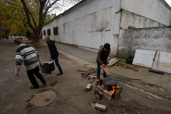 Zaposleni v enem izmed vrtcu v Mikolajevu med izpadom električne energije zaradi ruskega raketnega napada kuhajo hrano na drva.

FOTO: Valentin Ogirenko/Reuters
