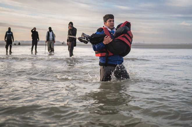 Migrant nosi otroka na tihotapsko ladjo pri mestu Dunkerque na severu Francije. Trenja med evropskimi državami pri azilnih in migracijskih vprašanjih ostajajo bolj ali manj enaka kot po izbruhu velike begunske krize leta 2015. FOTO: Sameer Al-doumy/AFP
