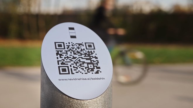 QR-koda s pripisom www.nevidnehise.si/baldahin je nameščena na začetku Lattermanovega drevoreda – pred rolkarskim parkom in parkiriščem v parku Tivoliju in s pogledom proti razrušenemu kopališču Ilirija. FOTO: arhiv Odprtih hiš Slovenije
